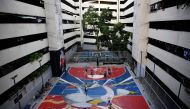 This photo taken on August 19, 2023 shows residents playing basketball on a court decorated with the FIBA World Cup 2023 logo, at a public housing project in Taguig city, suburban Manila. (Photo by Ted Aljibe / AFP)