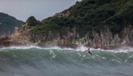 A surfer paddles over a wave generated by Typhoon Saola at a beach in Hong Kong on September 1, 2023.  (Photo by Dale De La Rey / AFP)