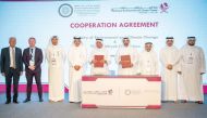 Minister of Environment and Climate Change H E Sheikh Dr. Faleh bin Nasser bin Ahmed bin Ali Al Thani and  Chairman of Al Attiyah Foundation and former Minister of Energy and Industry of Qatar, H E Abdullah bin Hamad Al Attiyah showing documents after signing the agreement. President of Qatar University Dr. Omar Al Ansari and other officials are also seen. 