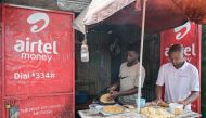 Food vendors prepare chapati inside a kiosk next to a sign advertising Airtel mobile money service, in Nairobi, on September 14, 2023. (Photo by Simon Maina / AFP)

