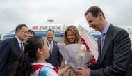 A handout picture released by the official Syrian Arab News Agency (SANA) shows Syria's President Bashar al-Assad (R) and First Lady Asma al-Assad (2-R) being welcomed upon their arrival at the airport in Beijing, on September 21, 2023. (Photo by SANA / AFP) /