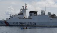 This photo taken on September 22, 2023 shows a wooden boat, with Philippine fisherman Arnel Satam on board, dwarfed by a Chinese coast guard vessel after he was intercepted for attempting to enter Scarborough Shoal in disputed waters of the South China Sea. (Photo by Ted Aljibe / AFP)