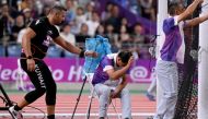 An official reacts in pain after his leg was injured by a stray hammer thrown by Ali Zankawi (L) who attempts to stem the bleeding. (Photo by William West / AFP)