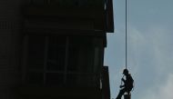 A worker cleans windows on a high-rise building in Beijing on October 10, 2023. Photo by Pedro PARDO / AFP
