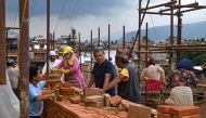 In this photograph taken on June 22, 2023, heritage conservationist and Kathmandu Valley Preservation Trust director Rohit Ranjitkar (4R) speaks with labourers at a reconstruction site in the Patan Durbar Square of Lalitpur district on the outskirts of Kathmandu. Photo by Prakash MATHEMA / AFP