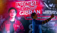 A supporter of Indonesian President Joko Widodo's son and current Surakarta City mayor, Gibran Rakabuming Raka takes a selfie with the latter's poster displayed at an event to raise support for his nomination as the vice presidential candidate ahead of the 2024 presidential elections in Jakarta on October 21, 2023. (Photo by Bay Ismoyo / AFP)
