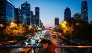 A woman walks on an overpass at the central business district in Beijing on November 14, 2023. (Photo by Jade Gao / AFP)