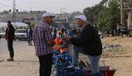 People wait near empty gas canisters to be filled with cooking gas from a tank that entered the Palestinian enclave on November 25, 2023. (Photo by Said Khatib / AFP)
