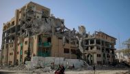Palestinians drive a motocycle past the destroyed building of the Islamic University in Gaza City on November 26, 2023 (Photo by Omar El-Qattaa / AFP)
