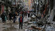 Palestinians walk amid debris of buildings hit in Israeli strikes, near Al-Zawiya market in Gaza City on November 27, 2023. (Photo by Omar El-Qattaa / AFP)