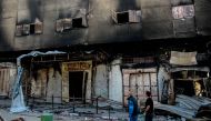 People walk past the Gaza municipality building in Gaza City on November 30, 2023. (Photo by Omar El-Qattaa / AFP)