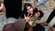 A woman holding a child mourns her baby girl killed in an Israeli strike in Rafah in the southern Gaza Strip, as she waits to receive the body for burial in the courtyard of the al-Najjar hospital on December 1, 2023. (Photo by Mohammed Abed / AFP)