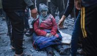 A woman injured in an Israeli strike sits amid the rubble in Rafah in the southern Gaza Strip on December 3, 2023. (Photo by Said Khatib / AFP)