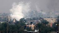 Smoke rises above buildings in Khan Yunis in the southern Gaza Strip on December 5, 2023. Photo by MAHMUD HAMS / AFP