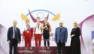 The podium winners of the women's 59kg event at the Qatar Cup IWF Grand Prix II, pose for a photograph with officials, yesterday.