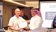 Qatar Gymnastics Federation President Ali Al Hitmi (right) presents a certificate to a participant.
