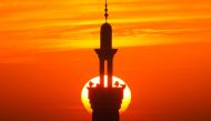 A picture taken from Rafah in the southern Gaza Strip on December 10, 2023, shows the minaret of a mosque silhouetted against the setting sun amid. (Photo by Mahmud Hams / AFP)