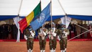 (FILES) Soldiers hold the UN and Malian flags during the ceremony of Peacekeepers' Day at the operating base of MINUSMA (The United Nations Multidimensional Integrated Stabilization Mission in Mali) in Bamako on May 29, 2018.(Photo by Michele CATTANI / AFP)
