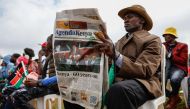 A member of public reads commemorative newspaper as he attends the national celebration marking Kenya's 60th anniversary of independence from Britain, known as Jamhuri Day, in Nairobi on December 12, 2023. (Photo by Simon Maina / AFP)