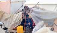 A Palestinian man warms under his makeshift tent at a camp for displaced people in Rafah, in the southern Gaza Strip where most civilians have taken refuge, on December 13, 2023. Photo by MAHMUD HAMS / AFP
