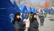 Earthquake-affected residents look on beside aid tents erected in a school compound at Gaoli village in Jishishan County in northwest China's Gansu province on December 20, 2023. (Photo by Pedro Pardo / AFP)
 
