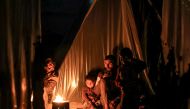 A man sits with children by a fire outside one of the tents housing Palestinians displaced by the conflict in Gaza, in Rafah in the southern Gaza Strip on December 18, 2023. (Photo by Mahmud Hams / AFP)
