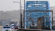 A Seoul Subway Line 4 metro train drives next to cars over the Dongjak Bridge, which runs across the Han River, in Seoul on December 7, 2023. (Photo by Anthony WALLACE / AFP)

