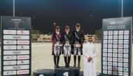 Michelle Grimes (centre), Maryam Ahmed Alsemaitt (left) and Saoud Ahmed Al Boinin pose on the podium with Hathab Deputy Director Faisal Al Kahla at QEF Outdoor Arena yesterday.   