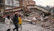 People walk past a collapsed building after an earthquake in Dahejia, Jishishan County in northwest China’s Gansu province on December 19, 2023. (Photo by Pedro Pardo / AFP)
