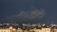 A picture taken from Rafah shows smoke billowing over Khan Yunis during Israeli bombardment in the southern Gaza Strip on December 24, 2023. (Photo by Said Khatib / AFP)
