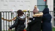 People lay flowers just in front of the ground floor flat where the bodies of a woman and her four children where discovered, in Meaux, eastern Paris, on December 26, 2023. (Photo by Alain Jocard / AFP)