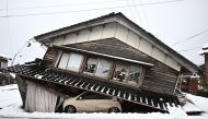 A damaged car lies underneath a collapsed building at Shika town in Hakui District, Ishikawa Prefecture on January 8, 2024 after a major 7.5 magnitude earthquake struck the Noto region on New Year's Day. (Photo by Philip FONG / AFP)