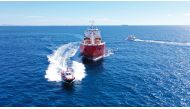 An aerial view of a pilot boat and large crude oil tanker cruising in the open ocean.