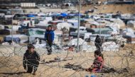 Displaced Palestinian kids play behind barbed wire on a sand dune overlooking a makeshift camp on the Egyptian border, west of Rafah in the southern Gaza Strip on January 14, 2024. (Photo by AFP)