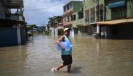 A man carrying a water bottle wades through the water in a flooded area of the Lote XV community in Duque de Caxias, Rio de Janeiro State, Brazil, on January 15, 2024. (Photo by Mauro PIMENTEL / AFP)
