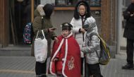 People are seen on a street in Beijing on January 17, 2024. (Photo by Pedro Pardo / AFP) 