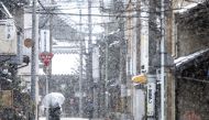 A woman walks on the street as it snows in Kyoto on January 25, 2024. (Photo by Philip FONG / AFP)
