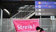 A participant walks past a banner of the German Civil Service Association (dbb beamtenbund und tarifunion) outside a terminal at Frankfurt Airport, Frankfurt am Main, western Germany on February 1, 2024, as flights are cancelled or delayed due to a nationwide strike of airport security staff. Photo by Kirill KUDRYAVTSEV / AFP