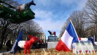 A national flag and cow scuptures are seen on a tractor as dairy farmers block the access to the Invalides esplanade during a protest against the agriculture policy in Paris on February 13, 2024. Photo by Emmanuel Dunand / AFP