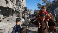 Palestinians walk past debris on February 22, 2024, following overnight Israeli air strikes in Rafah refugee camp in the southern Gaza Strip. (Photo by Mohammed Abed / AFP)