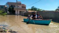 Residents row a boat to cross a flooded street after heavy rains in Gwadar in Balochistan province on March 2, 2024. (Photo by AFP)
