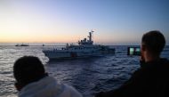 This photo taken on March 5, 2024 shows Philippine Coast Guard personnel filming a China Coast Guard vessel during a supply mission in the disputed South China Sea. Photo by JAM STA ROSA / AFP
