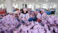 Employees work on a doll production line at a toy factory in Lianyungang, in eastern China's Jiangsu province on March 13, 2024. (Photo by AFP) 