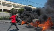A protester burns tires during a demonstration following the resignation of its Prime Minister Ariel Henry, in Port-au-Prince, Haiti, on March 12, 2024. (Photo by Clarens SIFFROY / AFP)
