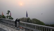 Tourists look out as high levels of air pollution obscure the view of Chiang Mai from atop Wat Phra That Doi Suthep temple on March 15, 2024. (Photo by Lillian SUWANRUMPHA / AFP)