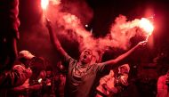 A supporter of Senegalese opposition leader Ousmane Sonko and presidential candidate Bassirou Diomaye Faye celebrates with flares after the two men were released from prison, in Dakar on March 14, 2024. (Photo by John Wessels / AFP)