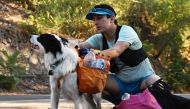 Sportsman and lawyer Gonzalo Chiang accompanied by his pet Sam, pick up plastic bottles during a plog run at Cerro San Cristobal in Santiago, on March 12, 2024. Photo by RODRIGO ARANGUA / AFP