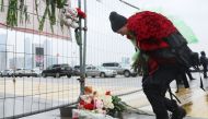A woman lays flowers at a makeshift memorial in front of the Crocus City Hall, A day after a gun attack in Krasnogorsk, outside Moscow, on March 23, 2024. Photo Credit: STRINGER / AFP.