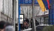 A man (L) holding a hand grenade stands on the porch of a police station in Yerevan on March 24, 2024, during an incident that the Caucasian country's government said was an attempt to seize the building. (Photo by KAREN MINASYAN / AFP)
