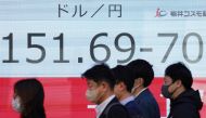 People walk past an electronic board showing the rate of the Japanese yen versus the US dollar along a street in Tokyo on March 27, 2024. Photo by Kazuhiro NOGI / AFP.